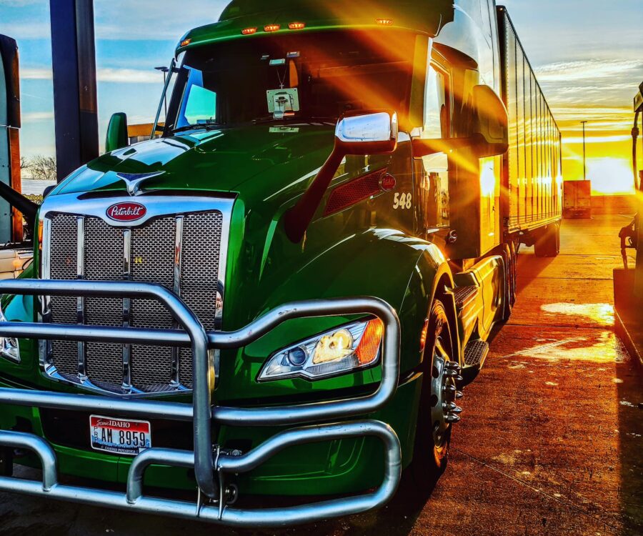 A green freight truck parked at a gas station in Syracuse, Nebraska